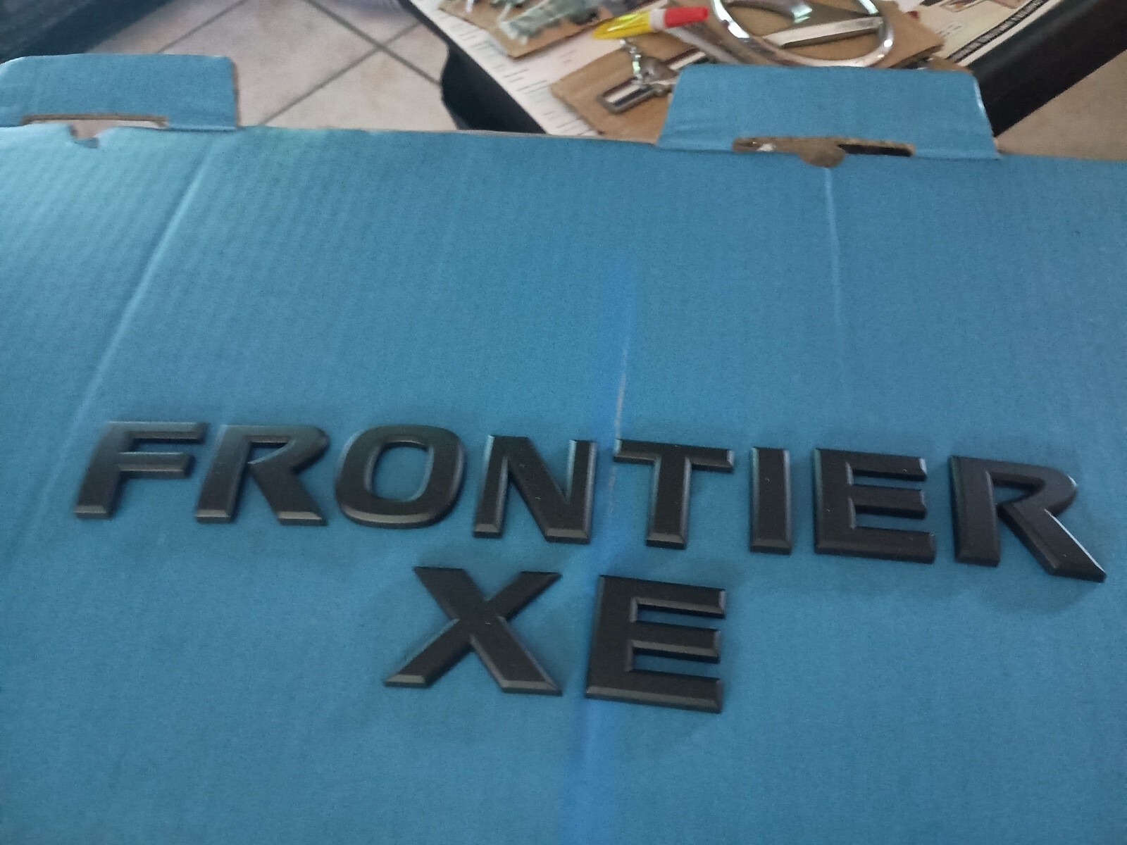 NISSAN FRONTIER XE PAINTED BLACK LETTERING 2005-16 REAR HATCH EMBLEM USED OEM